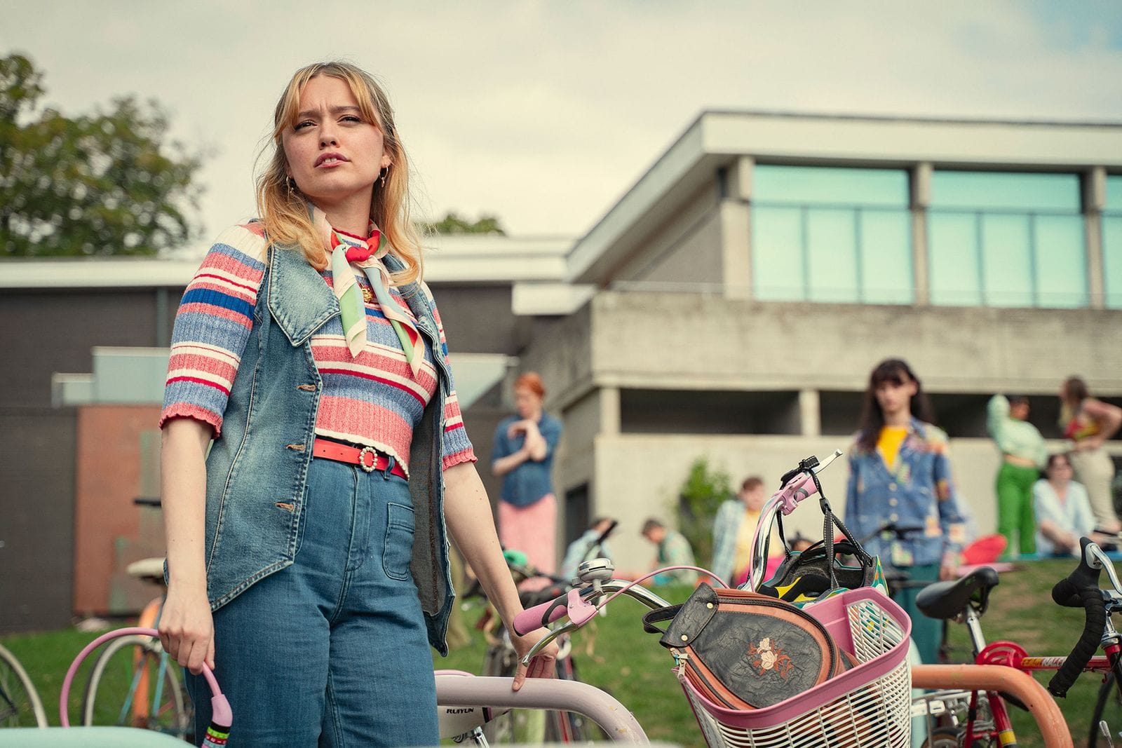 Aimee Lou Wood as Aimee Gibbs standing with a bicycle in Sex Education