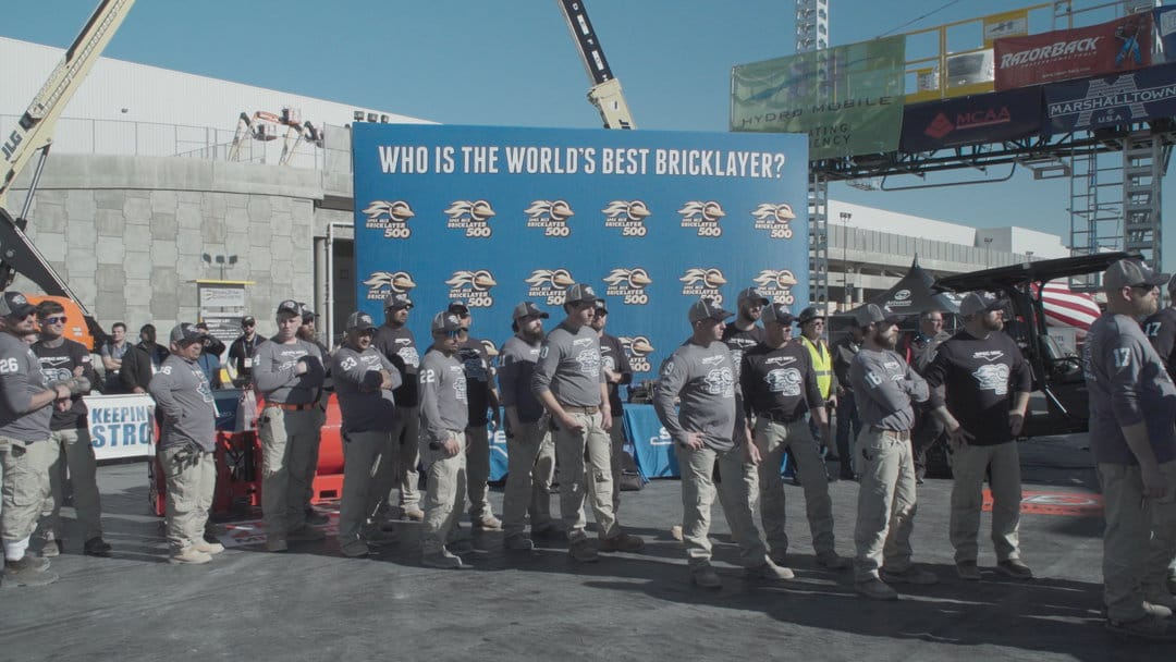 Bricklayers gathered beneath a competition banner in The History of Concrete