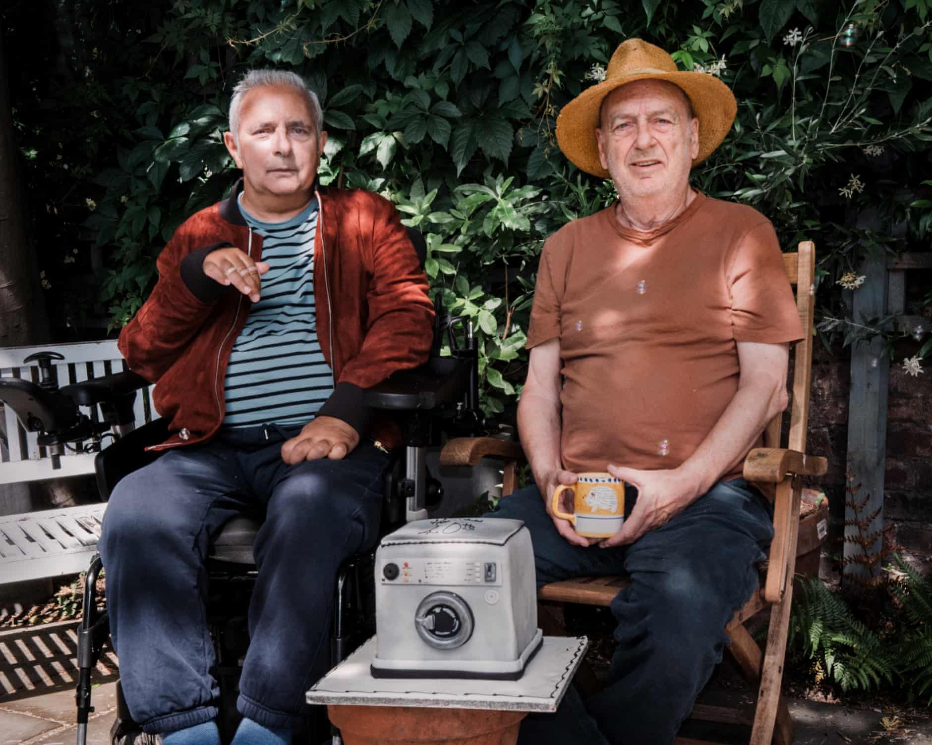 Hanif Kureishi and Stephen Frears sitting together beside a washing machine cake