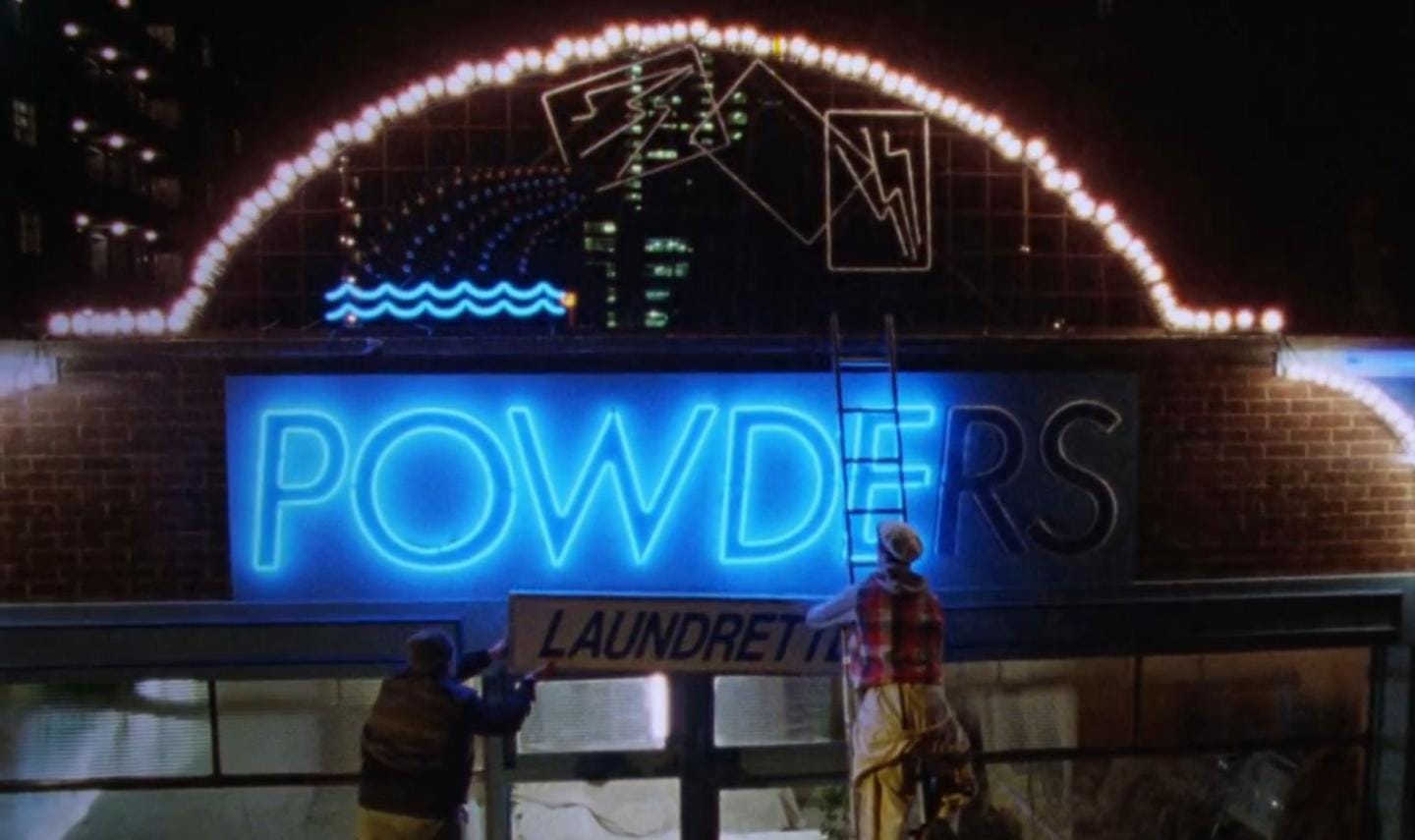 Omar and Johnny installing the laundrette sign beneath the blue Powders neon